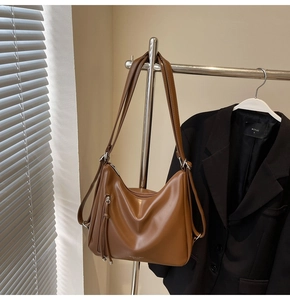 Detail view of brown PU leather tote bag with silver zippers and hanging straps