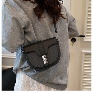 Detail showing the black contrast saddle bag with silver metal clasp and grid texture
