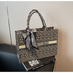 Close-up of canvas tote bag featuring geometric maze patterns and decorative silk scarf detail