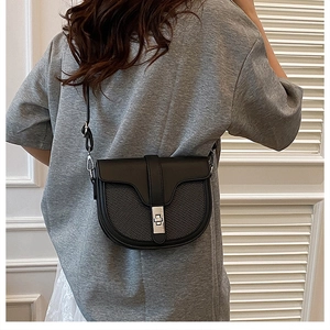 Detail of the black saddle bag showing woven texture panel and silver twist lock closure