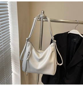 Close-up of light gray soft leather hobo bag with front zipper and long shoulder strap