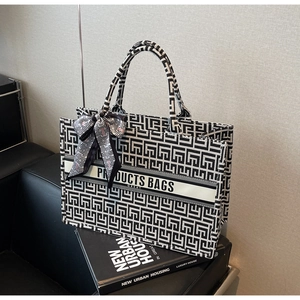 Detail of canvas tote bag featuring black and white geometric maze pattern and silk scarf
