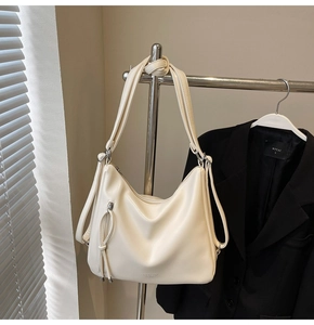 Close-up of cream faux leather tote bag with knot detail and Fashion & Bags text