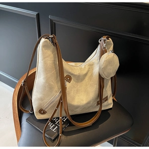 Detail of canvas tote bag featuring brown leather trim and a small round coin pouch attachment