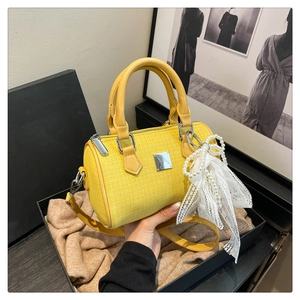Detail of yellow tweed Boston bag with pearl bow charm and silver metallic plate
