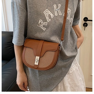 Detail view of the brown saddle bag with mixed leather and woven texture on model