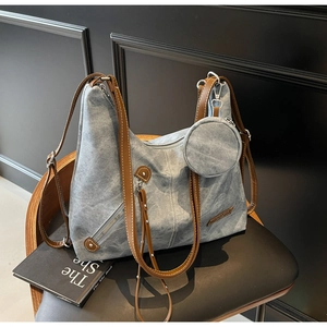 Blue denim tote bag with brown leather straps and a detachable round coin purse detail