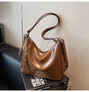 Detail of dark brown leather tote bag with long zipper tassels on a premium book