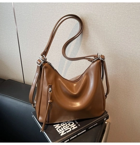 Detail of a brown leather hobo bag with side zipper pocket and silver metal hardware