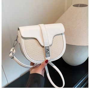 Detail of white saddle bag showing woven texture contrast and silver metal lock closure