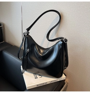 Detail of the black hobo shoulder bag with silver zipper and polished leather texture