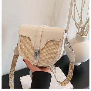 Detail of cream saddle bag featuring woven texture and embroidered geometric wide strap
