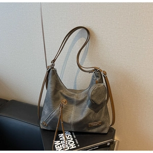 Detail of grey canvas hobo bag with white stitching, leather straps and fringe zipper