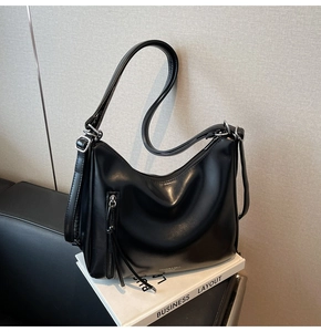 Detail of black glossy leather tote bag with adjustable strap and tassel zipper pocket