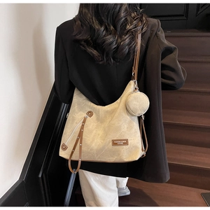 Detail of khaki canvas hobo bag with brown leather straps and small round coin purse charm