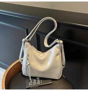 Detail view of cream leather hobo bag featuring vertical zip and knot tassel design