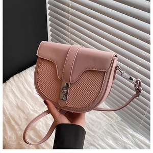 Close-up of pink saddle bag featuring woven texture detail and silver square metal lock