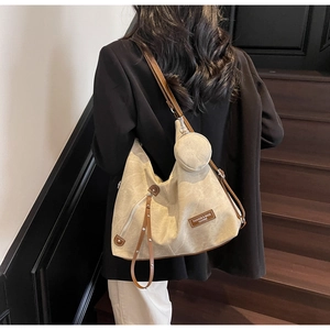 Detail of beige canvas tote bag with brown leather tag and mini round coin purse charm