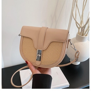 Detail of beige saddle bag showing contrast straw weaving and silver metal lock closure