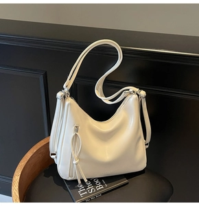Detail of cream large tote bag with tassel zipper and smooth leather texture on black seat