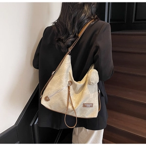 Detail of canvas tote bag with brown leather trim and detachable round coin purse charm