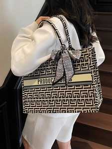 Canvas tote bag with black and white geometric pattern and shoulder strap shown on model