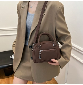 Borsa a tracolla marrone modello bowling con ciondolo a cuore indossata da modella
