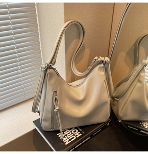 Detail of off-white Hobo shoulder bag featuring a vertical zip pocket and adjustable strap