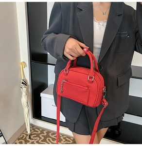 Mini borsa bowling rossa con ciondolo a cuore su modella con blazer grigio