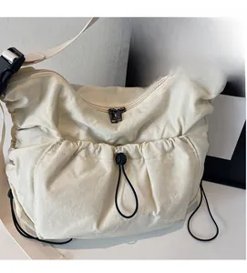 Detail view of beige nylon crossbody bag featuring drawstring pockets and dual zippers