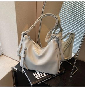 Detail of light gray soft leather tote with side zipper tassels and silver hardware accents