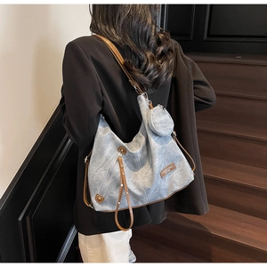 Detail of light blue canvas tote bag with brown leather straps and small round coin purse
