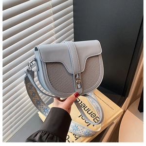 Detail of light blue saddle bag featuring leather stitching and silver twist lock buckle