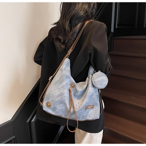 Detail view of light blue canvas tote bag with brown leather trim and round coin purse