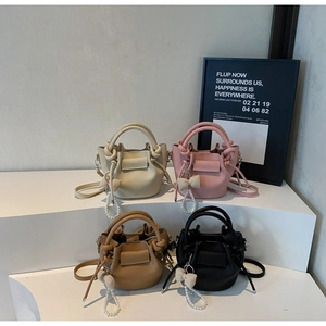 Litchi pattern leather bucket bags in four colors with pearl bow charms on white stairs