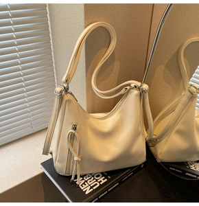 Chic cream tote bag with fringe detail and shoulder strap shown in an aesthetic mirror reflection