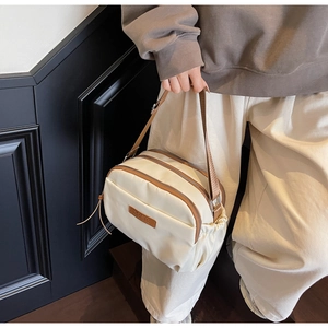 Detail of crossbody bag showing double zip compartments and brown leather trim