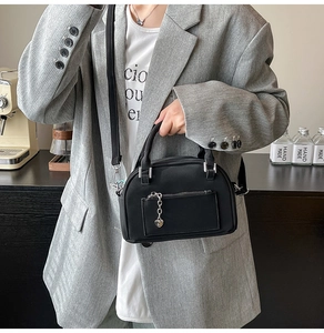 Détail du sac polochon noir avec pendentif en cœur et bandoulière réglable amovible