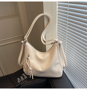 Detailed view of cream PU leather shoulder bag with zipper trim and drawstring accents