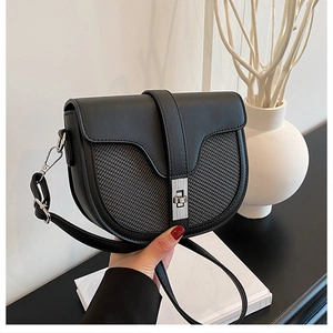 Macro detail of black saddle bag featuring woven texture contrast and silver twist lock