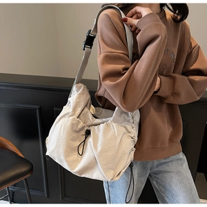 Detail of light beige pleated crossbody bag with drawstring and wide adjustable strap
