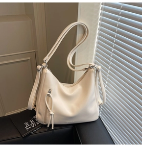 Close-up of cream white leather hobo bag texture with zipper and soft shadow lighting