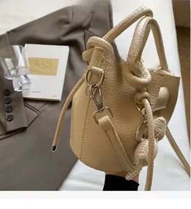 Detail of lychee pattern bucket bag featuring pearl charms and a plaid bow accessory