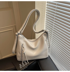 Detail of adjustable strap and front zipper on cream minimalist shoulder bag