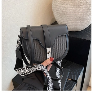 Detail of contrast saddle bag with bohemian woven strap and silver metal twist lock