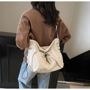 Detailed view of the drawstring closure and pleated texture of the beige hobo bag