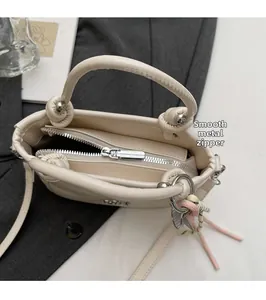 Detail des glatten silbernen Reißverschlusses an einer cremefarbenen Eimer-Tasche