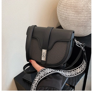 Detail of black saddle bag with textured panel and ethnic geometric wide shoulder strap