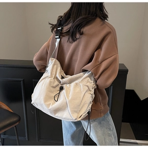 Detail of adjustable black strap and toggle closure on cream canvas crossbody bag