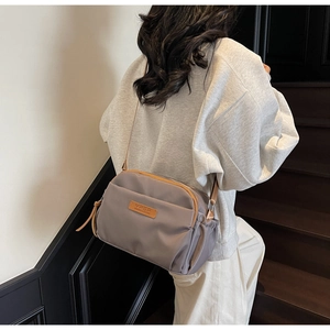 Detail of taupe nylon crossbody bag with leather trim and adjustable brown strap
